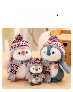 Close-up of cute plush penguins with knitted hats, scarves and daisy details on wood