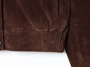 Detailed macro of dark brown faux suede jacket featuring elastic hem and double stitching