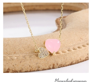Close-up of pink heart gemstone and micro-inlaid zirconium pendant on gold chain