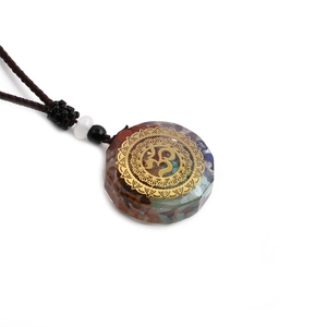 Detail of 7 chakra stones in a clear 3D resin pendant with golden Om mandala on woven cord