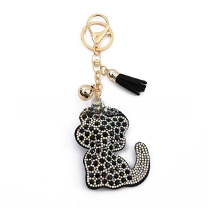 Close-up of crystal rhinestone cat keychain with black leather tassel and gold bell charm