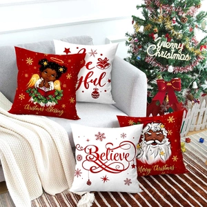 Set of four Christmas pillow covers with Santa and angel prints on a gray sofa