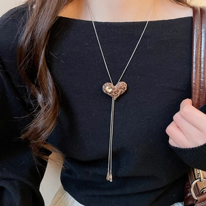 Detail of a leopard print heart pendant with square crystal and fringe tassels on a necklace