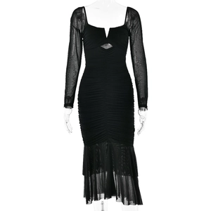 Detail showing the sheer mesh stitching and fishtail hem of this elegant black dress