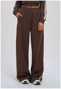 Detail of deep brown sweatpants showing loose fit and side double white stripes decoration