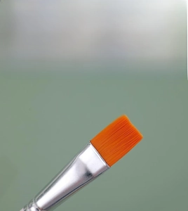 Close-up of premium orange nylon bristles and silver metal ferrule of the art brush