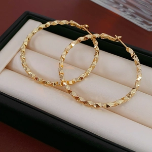 Close-up of golden irregular geometric hoop earrings in a black jewelry gift box