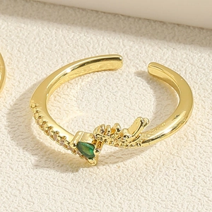 Detail of gold open ring featuring green heart gem and intricate dragon carving