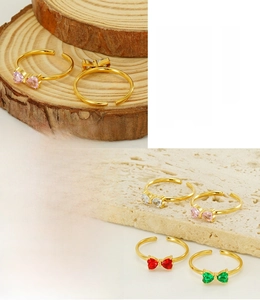 Dettaglio di anelli a fiocco con pietre a cuore placcati oro 18K in rosa, bianco e rosso