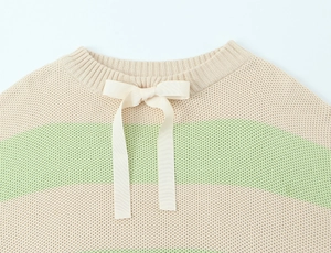 Detail of striped knit sweater showing ribbon bow on the neckline and woven texture