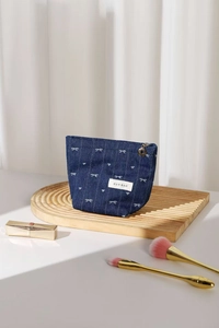 Close-up of denim cosmetic bag with white bow embroidery and flower-shaped zipper puller