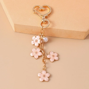 Detail of pink enamel flowers and white pearl charm on a golden heart keychain