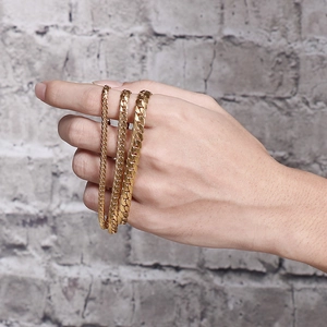 Three widths of gold stainless steel Cuban link chains shown held in hand
