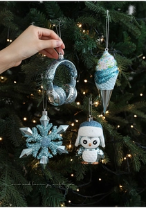 Detailed view of ice blue glitter Christmas ornaments featuring penguins and snowflakes