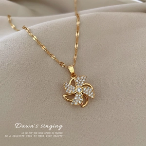 Detailed view of a gold-tone spinning windmill pendant necklace with sparkling crystals