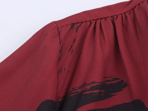 Makroaufnahme der weinroten Kleid Schulter mit schwarzen Tintentupfen und Falten am Ausschnitt
