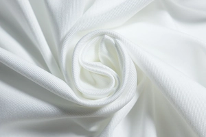 Macro shot of white high-density knit dress fabric with spiral drapes and smooth texture