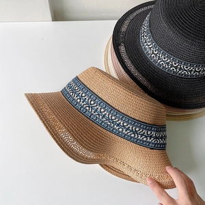 Dettaglio di cappelli di paglia intrecciati con nastri decorativi a motivi etnici chic