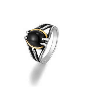 Detail of silver and gold toned ring with a black oval gemstone inlay from a side angle