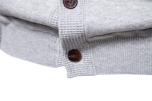 Close-up of grey knit cardigan hem featuring ribbed texture and dark brown buttons