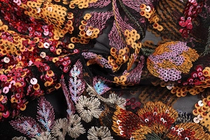 Macro shot of colorful sequin embroidery on high-density black mesh dress fabric