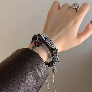Macro shot of Goth Y2K silver chain necklace with red heart gemstone and cross charms
