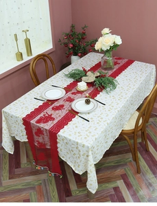 Detail view of red lace table runner with colorful tassels on a white tablecloth