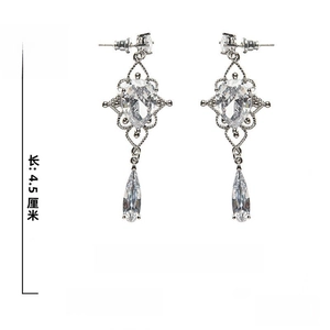 Detailed view of pear-cut zircon drop earrings with baroque hollow patterns and silver pins