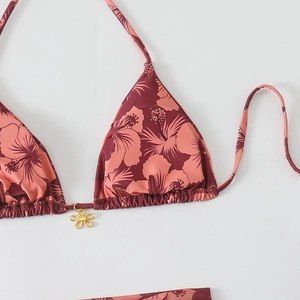 Detail of floral bikini top featuring hibiscus print and golden flower pendant detail