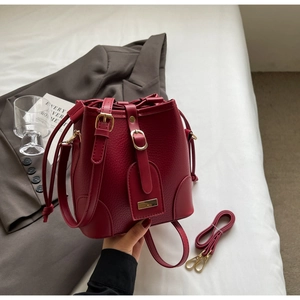 Detail of dark red bucket bag showing lychee grain leather and gold metal hardware