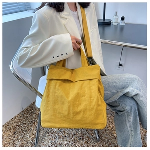 Detailed view of lightweight yellow nylon tote bag with adjustable shoulder strap and texture