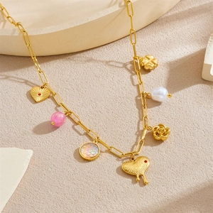 Gold stainless steel chain necklace with heart, rose, and pearl charms on beige props
