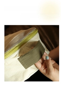 Detail of reinforced army green handle and breathable mesh on cream travel organizer bag