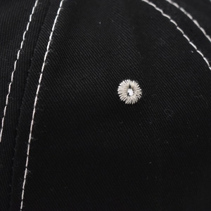 Close-up of black cotton baseball cap showing white contrast stitching and embroidered eyelet