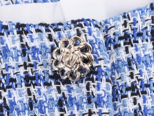 Vue macro détaillée du tissu en tweed bleu et d'un bouton doré orné sur le gilet
