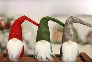Three plush Christmas gnomes in red, green and grey colors on a rustic wooden tray