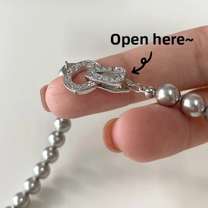 Detail of grey pearl necklace featuring a zircon-encrusted metal clasp closure