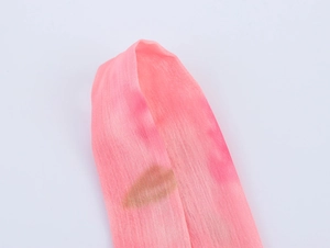 Dettaglio della trama del tessuto chiffon rosa con stampe di labbra dorate lucide