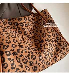 Detailed close-up of leopard print canvas tote bag with brown faux leather shoulder strap