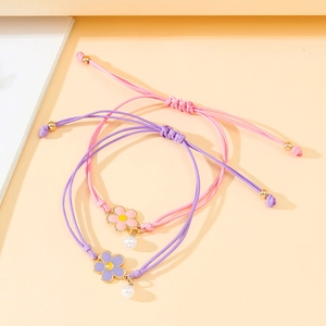Detail of woven floral friendship bracelets with pearl pendants and gold metal beads