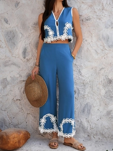 Détail du haut bleu sans manches et du pantalon large avec broderie en dentelle blanche