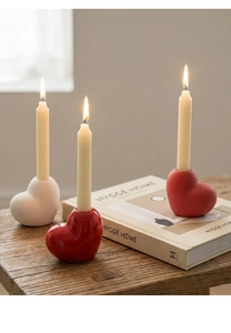 Three-piece ceramic heart candle holders in red and white finishes on a wooden desk