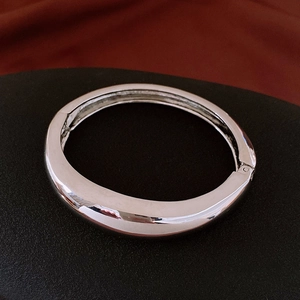 Gros plan détaillé d'un bracelet jonc argenté poli avec un design minimaliste articulé