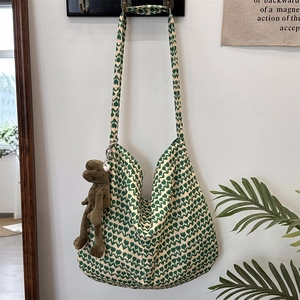 Detail view of floral cotton canvas tote bag with frog plush charm on a white wall