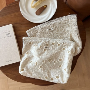 Beige floral lace and embroidery makeup bags with simple wish label on a wooden table