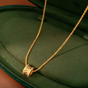 Macro detail of 18k gold plated cylinder pendant with zircons on green velvet box