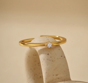 Close-up of minimalist gold open ring featuring a sparkling micro-set clear gemstone