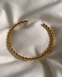 Minimalist twisted cable open bangle in 18k gold plated stainless steel on white fabric