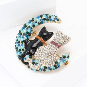 Detailed close-up of crescent moon brooch with cats, rhinestones and turquoise beads