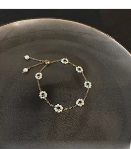 Detailed macro of gold-plated flower bracelet with emerald stones and pearl petals